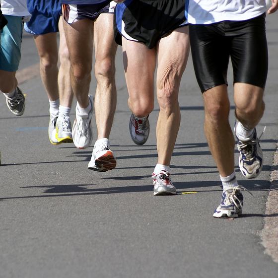 Группа бегунов бежит по дорожке. Тренировка бег. Бег по меткам. Спорт проблема с ногами. Эстафета в одних штанах.